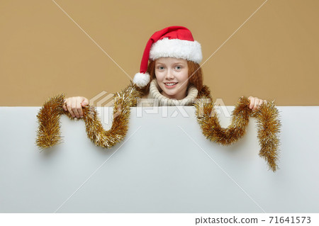 happy red-haired girl in a Santa hat with a white Billboard on which you can place your text. advertising concept for Christmas and New year 71641573