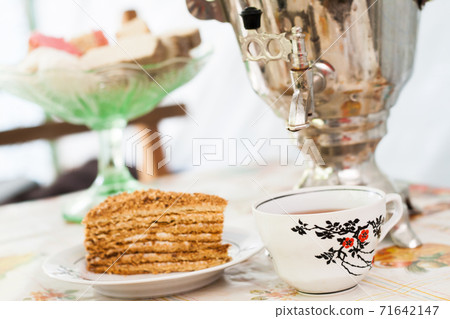 piece of cake honey cake on a plate, a cup of tea and a samovar piece of cake honey cake on a plate, a cup of tea and a samovar 71642147