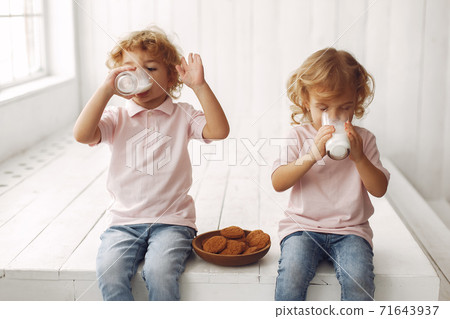 Cute children eatting cookies and drinking milk Cute children eatting cookies and drinking milk 71643937