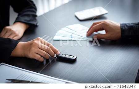Car sales representative or sales manager submits a car key to a client who has approved financial loans with the company, Approval of financial and banking loans concept. 71648347