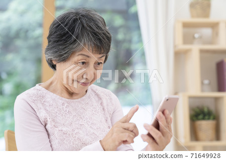 Senior female using a smartphone 71649928