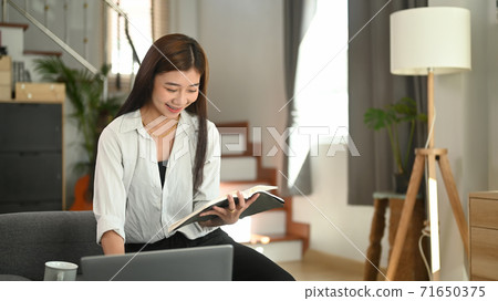A beautiful caucasian woman having rest on the couch and reading a book at home. A beautiful caucasian woman having rest on the couch and reading a book at home. 71650375