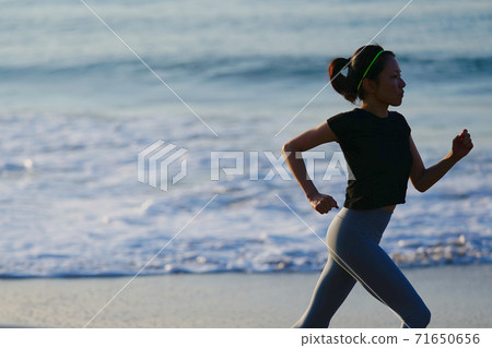 在後台與冉冉升起的太陽在海灘上慢跑的女人 在後台與冉冉升起的太陽在海灘上慢跑的女人 71650656