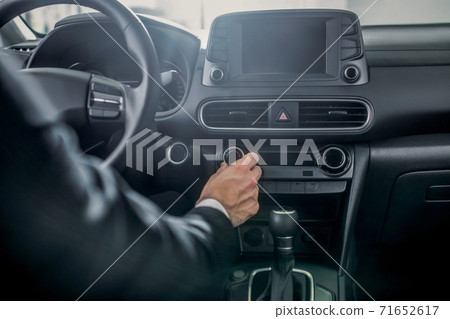 Close-up of male hands adjusting car settings 71652617