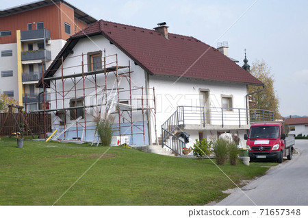 Facade thermal insulation and painting works, scaffolding in a village 71657348