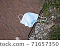 used face mask drop on ground grass floor, save the nature. garbage. 71657350