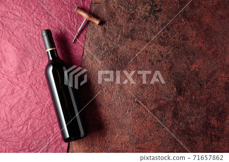 A bottle of red wine on an old rough background. A bottle of red wine on an old rough background. 71657862