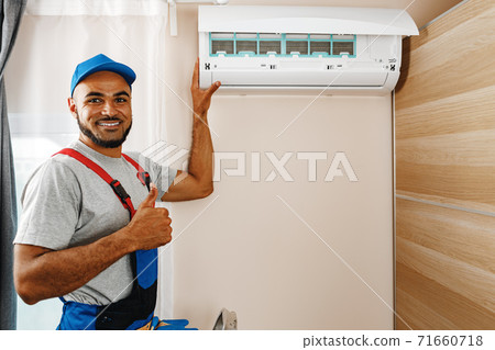 Professional repairman installing air conditioner in a room 71660718