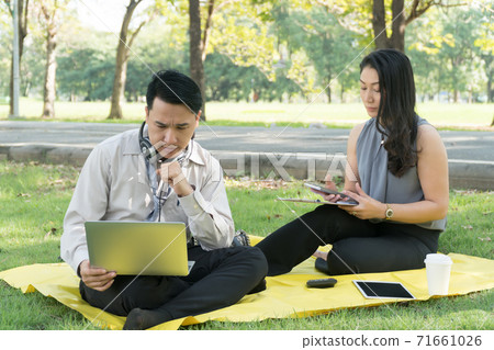 business man and woman sitting relaxed in shady park. But there is talk. Analysis of business plan. 71661026
