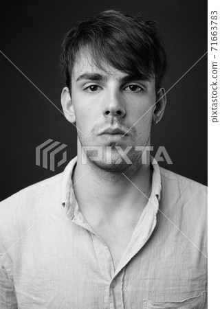 Studio shot of young handsome man against gray background Studio shot of young handsome man against gray background 71663783