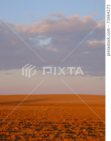 Cloudy evening sky over an empty agricultural field. Bright sunset landscape. 71664273