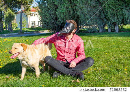 boy wearing old style virus mask   with his dog playing at garden 71668282