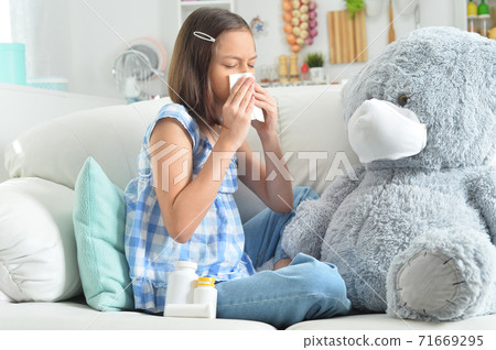Girl coughing with toy bear in facial mask Girl coughing with toy bear in facial mask 71669295