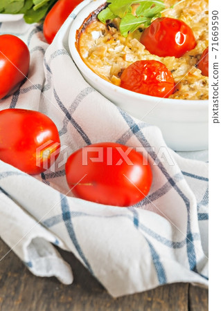 Casserole with zucchini, tomatoes and greens on a napkin on a wooden table Casserole with zucchini, tomatoes and greens on a napkin on a wooden table 71669590