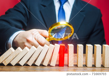 A businessman is studying the reason for stopping the fall of dominoes. Find the stop reason the work process. Error or failures, force majeure. Elimination of obstacles malfunctions, analysis A businessman is studying the reason for stopping the fall of dominoes. Find the stop reason the work process. Error or failures, force majeure. Elimination of obstacles malfunctions, analysis 71669703
