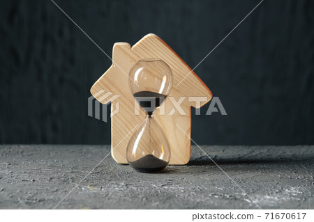 Wooden model of house and hourglass. Saving and buying a property concept Wooden model of house and hourglass. Saving and buying a property concept 71670617