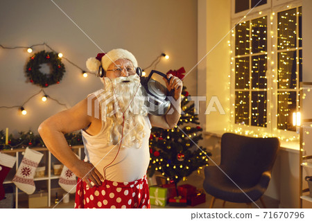 Funny granddad with Santa beard, headphones and boombox having fun on Christmas night at home 71670796