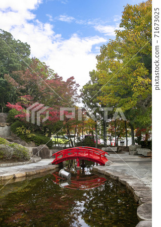 Take a picture of the park in front of Okayama Momotaro Airport, which has begun to turn red, with the sky and a pond. 71673025