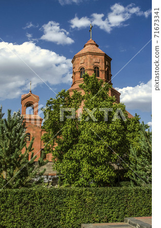 View from the Park behind the trees of the bell tower and the main dome with a copper cross and arched windows on the facade of the Cathedral of  the Holy Martyrs in Gyumri View from the Park behind the trees of the bell tower and the main dome with a copper cross and arched windows on the facade of the Cathedral of  the Holy Martyrs in Gyumri 71673341