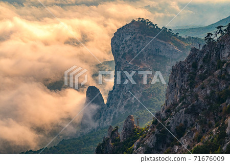 Majestic orange sunset over the rocky mountains and the valley in fog and clouds. Creamy fog covered the mountain valley in sunset light. Misty sunset over Crimea Mountains Majestic orange sunset over the rocky mountains and the valley in fog and clouds. Creamy fog covered the mountain valley in sunset light. Misty sunset over Crimea Mountains 71676009