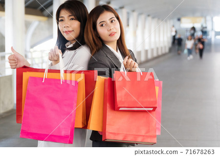 Happiness, consumer, sale and people concept. Attractive two young woman holding shopping bags 71678263