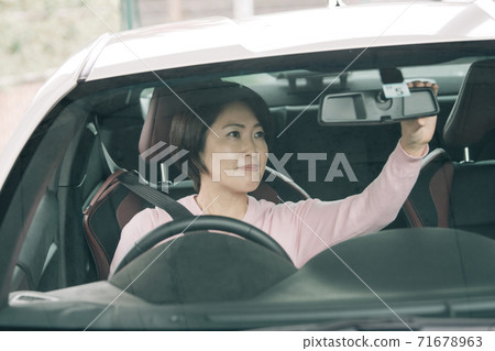 A woman driving a car ・ A woman who corrects the angle of the rearview mirror 71678963