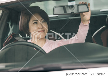 A woman driving a car ・ A woman who corrects the angle of the rearview mirror A woman driving a car ・ A woman who corrects the angle of the rearview mirror 71678964