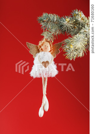 White angel toy on a Christmas tree on a red background. 71680160