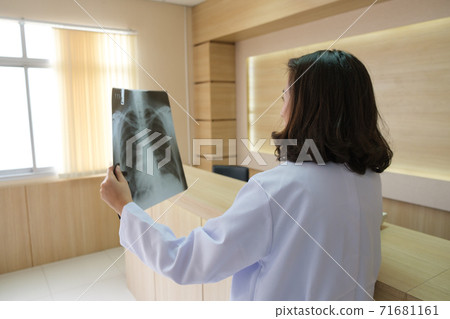 The female doctor was looking at the x-ray film and on the phone The female doctor was looking at the x-ray film and on the phone 71681161