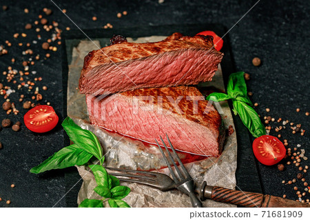 Rare beef steak. Spices and herbs on a dark background. Juicy and appetizing meat. 71681909