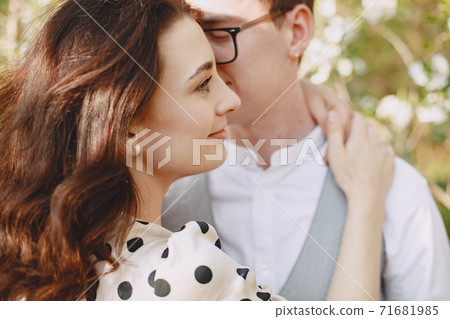 Young man and woman couple in a blooming garden Young man and woman couple in a blooming garden 71681985