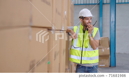 Professional cargo worker talks on portable radio to contact another worker Professional cargo worker talks on portable radio to contact another worker 71681986