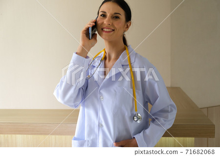 A female doctor is talking on the phone to inquire about the symptoms of the physical patient A female doctor is talking on the phone to inquire about the symptoms of the physical patient 71682068