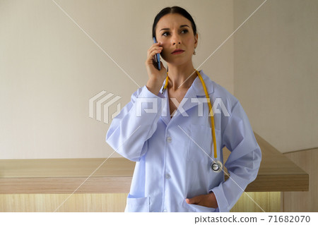 A female doctor is talking on the phone to inquire about the symptoms of the physical patient A female doctor is talking on the phone to inquire about the symptoms of the physical patient 71682070