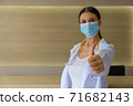 A female doctor wearing a medical mask raising his thumbs. 71682143