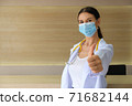 A female doctor wearing a medical mask raising his thumbs. 71682144