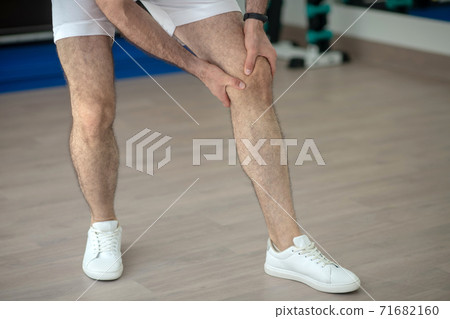 Close-up of male hands massaging painful knee in the gym 71682160