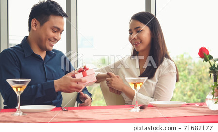 Romantic couple giving gift to lover at restaurant 71682177