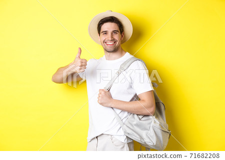 Tourism, travelling and holidays concept. Happy man going on vacation, holding backpack and showing thumb up, smiling satisfied, standing against yellow background Tourism, travelling and holidays concept. Happy man going on vacation, holding backpack and showing thumb up, smiling satisfied, standing against yellow background 71682208