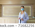 A female doctor wearing a mask is standing at the reception. 71682256