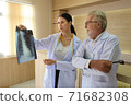 Two doctors are looking at the patient's history and X-Ray film and discussing the patient's illness. 71682308