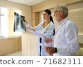 Two doctors are looking at the patient's history and X-Ray film and discussing the patient's illness. 71682311