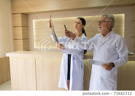 Two doctors were looking at the patient's record and discussing the patient's illness. Two doctors were looking at the patient's record and discussing the patient's illness. 71682312