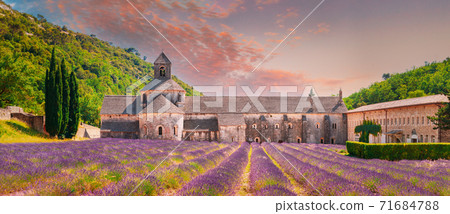 Notre-dame De Senanque Abbey, Vaucluse, France. Beautiful Landscape Lavender Field And An Ancient Monastery Abbaye Notre-dame De Senanque. Elevated View, Panorama. Altered Sunset Sky Notre-dame De Senanque Abbey, Vaucluse, France. Beautiful Landscape Lavender Field And An Ancient Monastery Abbaye Notre-dame De Senanque. Elevated View, Panorama. Altered Sunset Sky 71684788