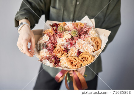 Beautiful bouquet of mixed flowers in womans hands. the work of the florist at a flower shop. Delivery fresh cut flower. European floral shop. Beautiful bouquet of mixed flowers in womans hands. the work of the florist at a flower shop. Delivery fresh cut flower. European floral shop. 71685898