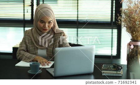 Asian muslim businesswoman working with laptop and supplies Asian muslim businesswoman working with laptop and supplies 71692341