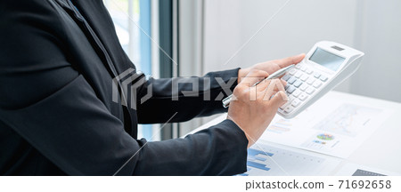 Business woman are working by reviewing the numeric data from the graph using a calculator Business woman are working by reviewing the numeric data from the graph using a calculator 71692658