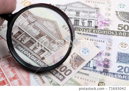 Suriname money in a magnifying glass Suriname money in a magnifying glass 71693042
