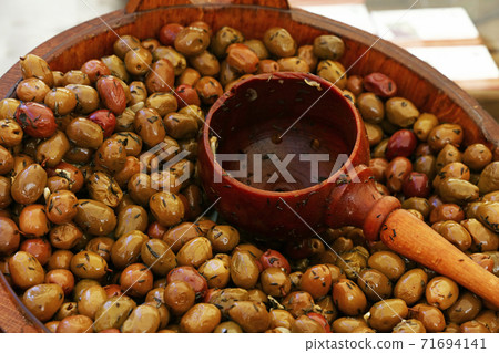 Pickled green olives and wooden scoop in a barrel 71694141