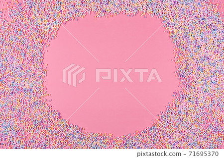 Round frame made of pastel color balls on pink. Styrofoam or Polystyrene foam background. Mix of colorful sugar balls for sweets decoration. Rainbow colored sugar chips, dragee spins, confectionery. Round frame made of pastel color balls on pink. Styrofoam or Polystyrene foam background. Mix of colorful sugar balls for sweets decoration. Rainbow colored sugar chips, dragee spins, confectionery. 71695370